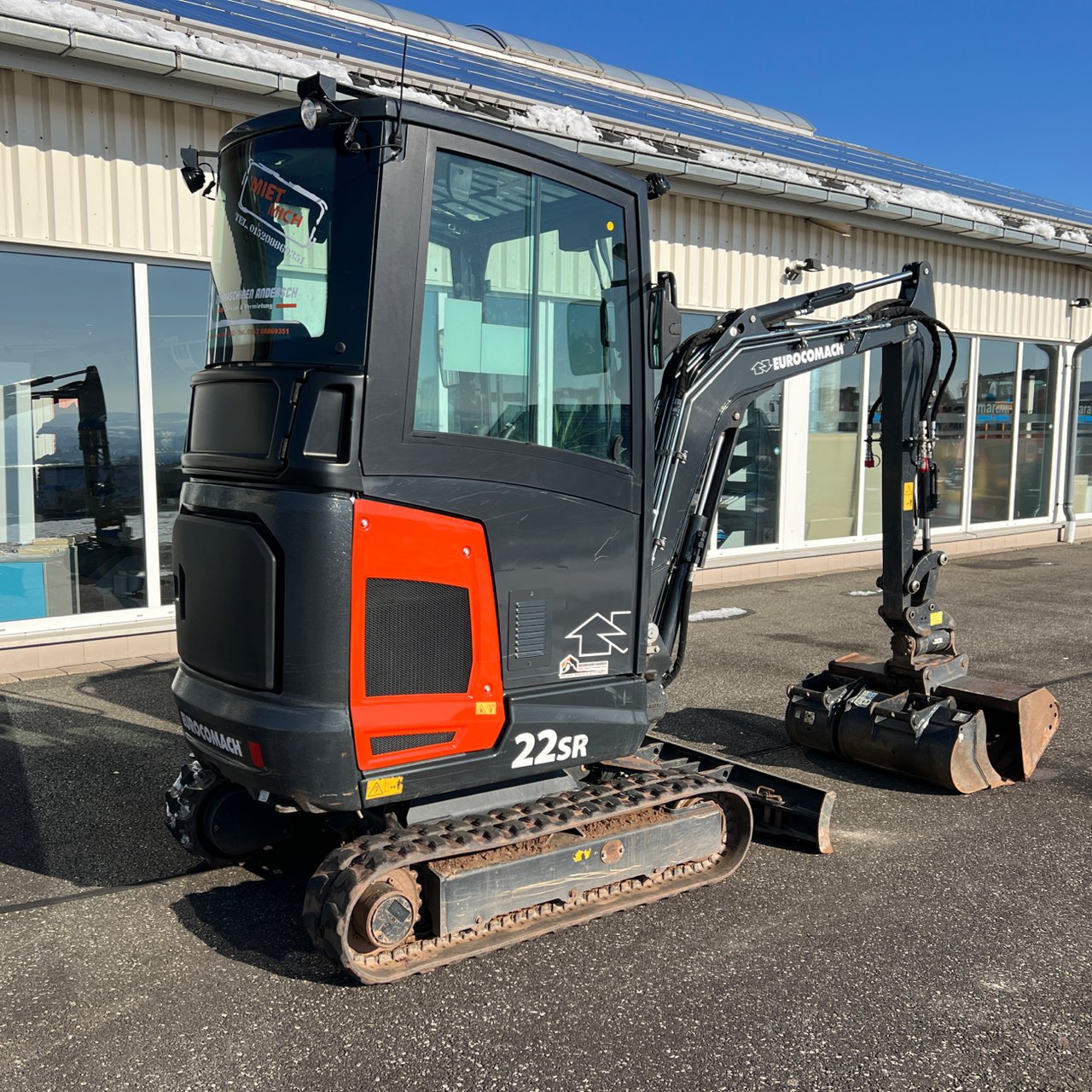 Schwarzer und oranger Yanmar 22SR Minibagger mit Schaufel auf einem Parkplatz.